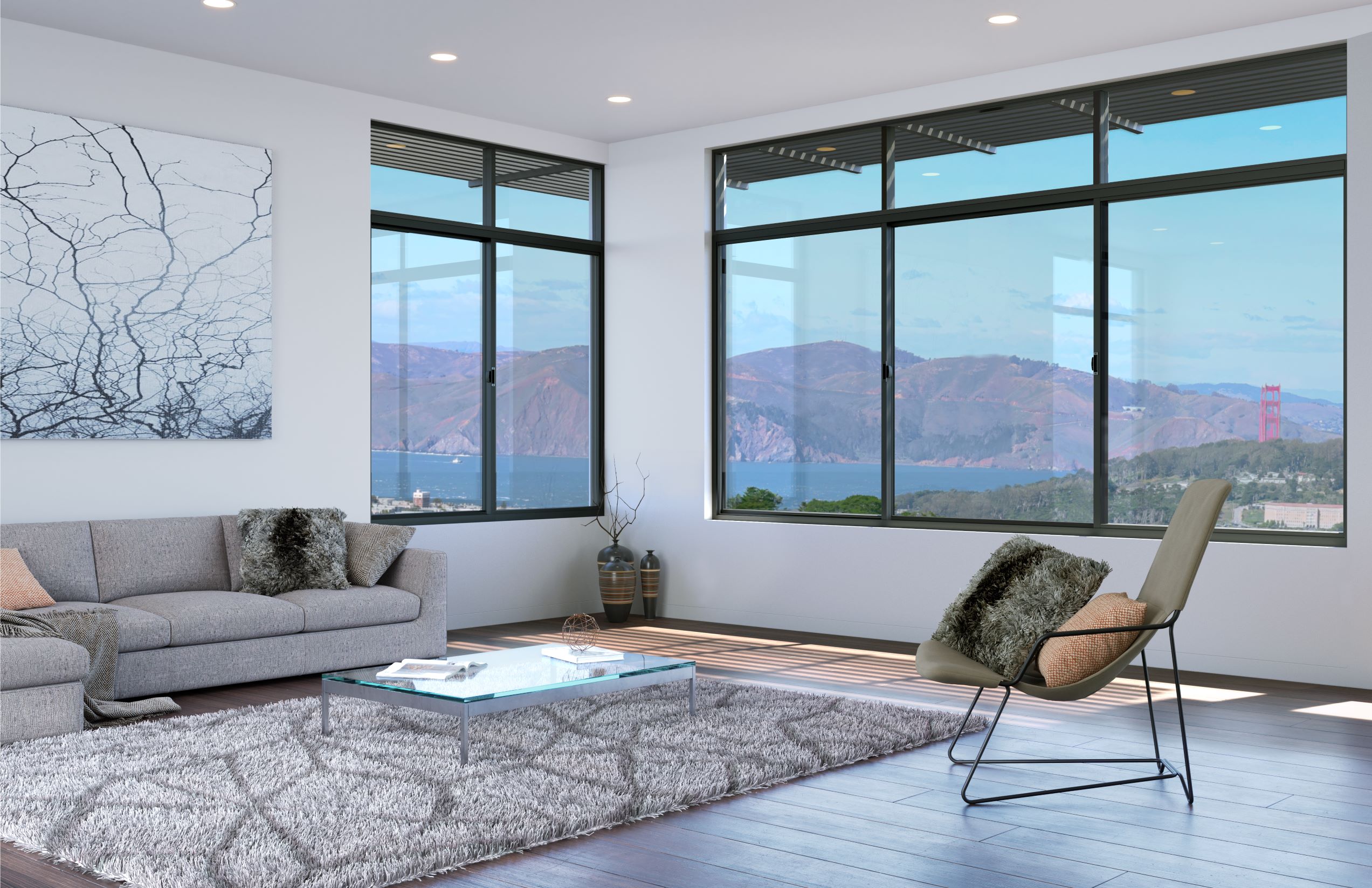 Modern living room with large windows offering a scenic view of hills and a distant bridge. The room features a gray sofa, a glass coffee table, a shag rug, and a modern chair with cushions.